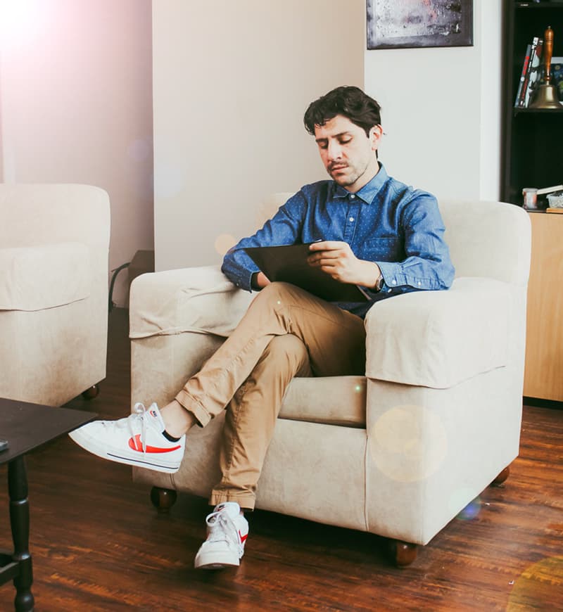 Hombre en sillón con tablet revisando contenido